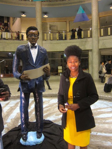 21 januari 2018 › Rhode Makoumbou dans la Galerie Ravenstein avec sa sculpture «Patrice Lumumba, le discours d'Indépendance du 30 juin 1960».