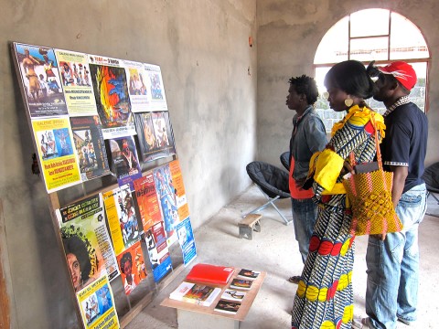 13 januari 2010 › Trois visiteurs dans l'atelier de Rhode Makoumbou à Mansimou, devant un panneau présentant les affiches de ses expositions.