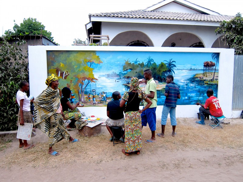 24 augustus 2012 › La famille et les voisins assistent à la création de la fresque murale «Le village de pêcheurs» réalisée par Rhode Makoumbou.
