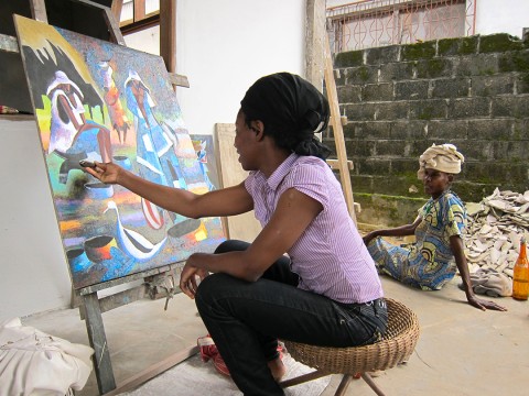 10 janvier 2010 › Rhode Makoumbou peignant dans son atelier à Mansimou. À droite : sa mère, Élisabeth Makoumbou.