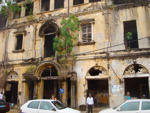 Rhode Makoumbou devant une maison coloniale en ruine située à Grand-Bassam