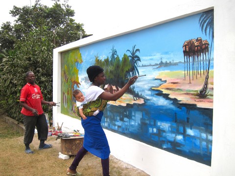 20 août 2012 › Rhode Makoumbou portant son fils Quentin et réalisant en même temps la fresque murale «Le village de pêcheurs».