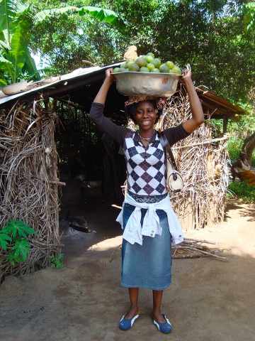 Rhode Makoumbou transportant sur la tête une grande casserole remplie d'oranges