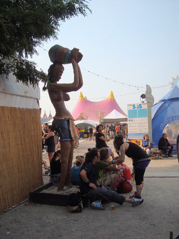 28 juin 2009 › Des festivaliers de Couleur Café au pied de la sculpture de Rhode Makoumbou «L'eau arrive au village».