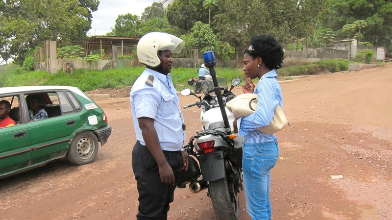 26 maart 2010 › Rhode Makoumbou en discussion avec un policier motorisé, sur le parcours de son exposition itinérante «Trait-d'Union».